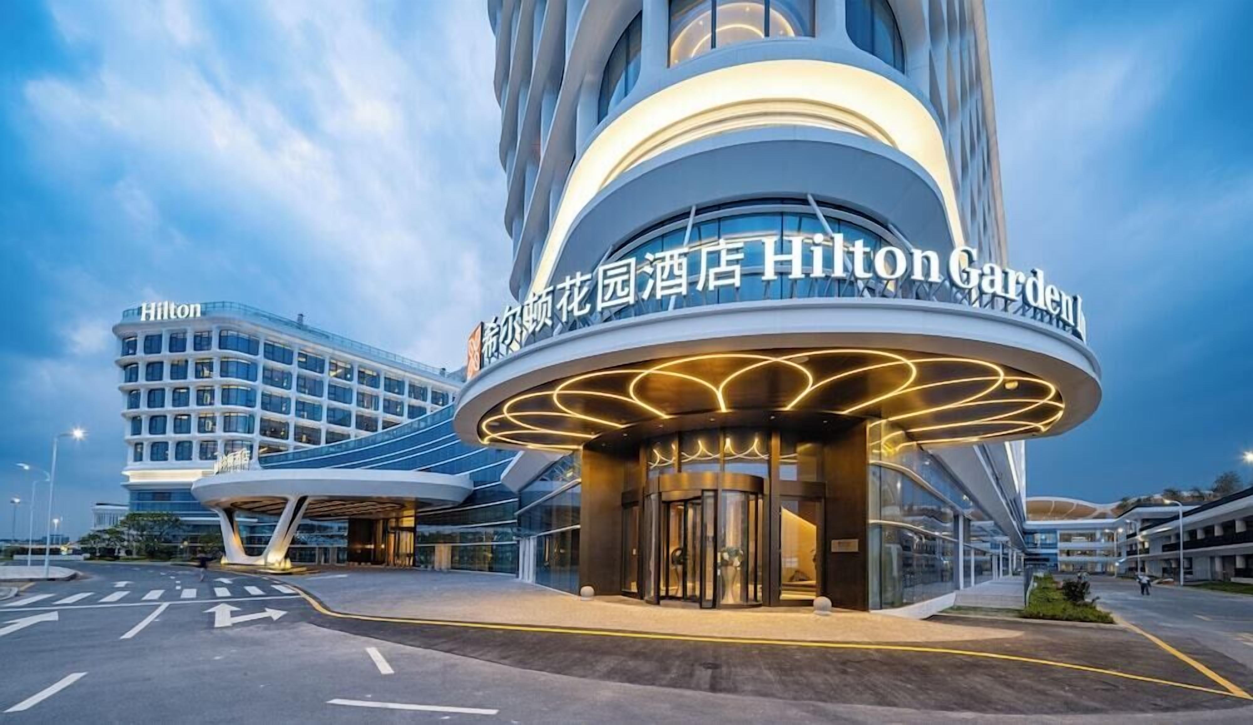 A modern hotel entrance with a curved facade and illuminated signage.