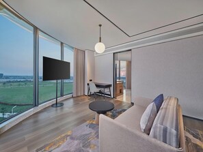 A modern hotel room with a large window, a flat-screen TV, a sofa, and a dining area. - Hilton Garden Inn Guangzhou Baiyun Airport (Guangzhou)