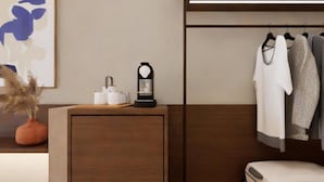 A modern room with a wooden desk, a hanging coat rack, and a suitcase on the floor. - Arato by E.geo (Kos)