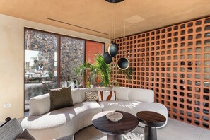 A modern living room with a sectional sofa, a coffee table, and a decorative wall with a geometric pattern. - Arato by E.geo (Kos)