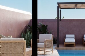 Zona de piscina con sillas de mimbre, un área de estar techada y vista al cielo.