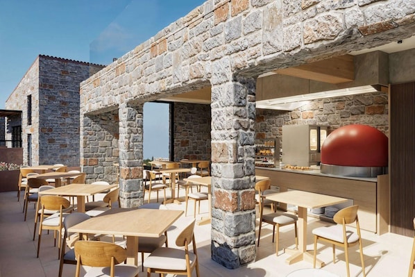 An outdoor dining area with stone pillars, wooden tables, and chairs. - Volta Seaside Hotel - Adult-only (Hersonissos)