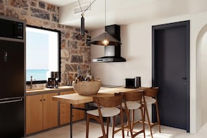 Una cocina moderna con una pared de piedra, una puerta negra y vista al mar.