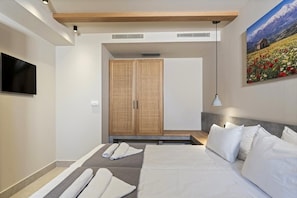 A modern hotel room with a bed, a flat-screen TV, a large painting, and a wardrobe. - Volta Seaside Hotel - Adult-only (Hersonissos)