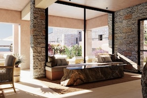 Una sala de estar moderna con una pared de piedra, un ventanal y una zona de estar con una mesita de centro.