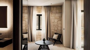Une salle de bain moderne avec un grand miroir, une table ronde et un mur en pierre.