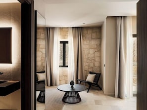 A modern bathroom with a large mirror, a round table, and a stone wall.