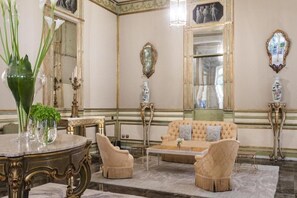 A room with a round table, two armchairs, a sofa, and a mirror.