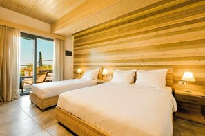 Habitación de hotel con dos camas, un balcón con vistas y paneles de madera en las paredes.