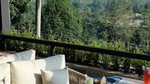A dining table set with plates, cutlery, and a pitcher, overlooking a lush landscape with trees and hills. - Laska Hotel and Resort Ciater (Ciater)