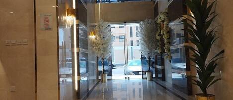 A hotel entrance with a glass door, a sign indicating an exit, and a potted plant on the right.