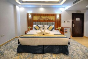 A hotel room with a large bed, a wooden headboard, and a decorative wall piece. - Almarzam Hotel (Madinah)