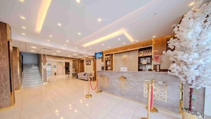 A hotel lobby with a reception desk, a staircase, and a seating area. - Almarzam Hotel (Madinah)