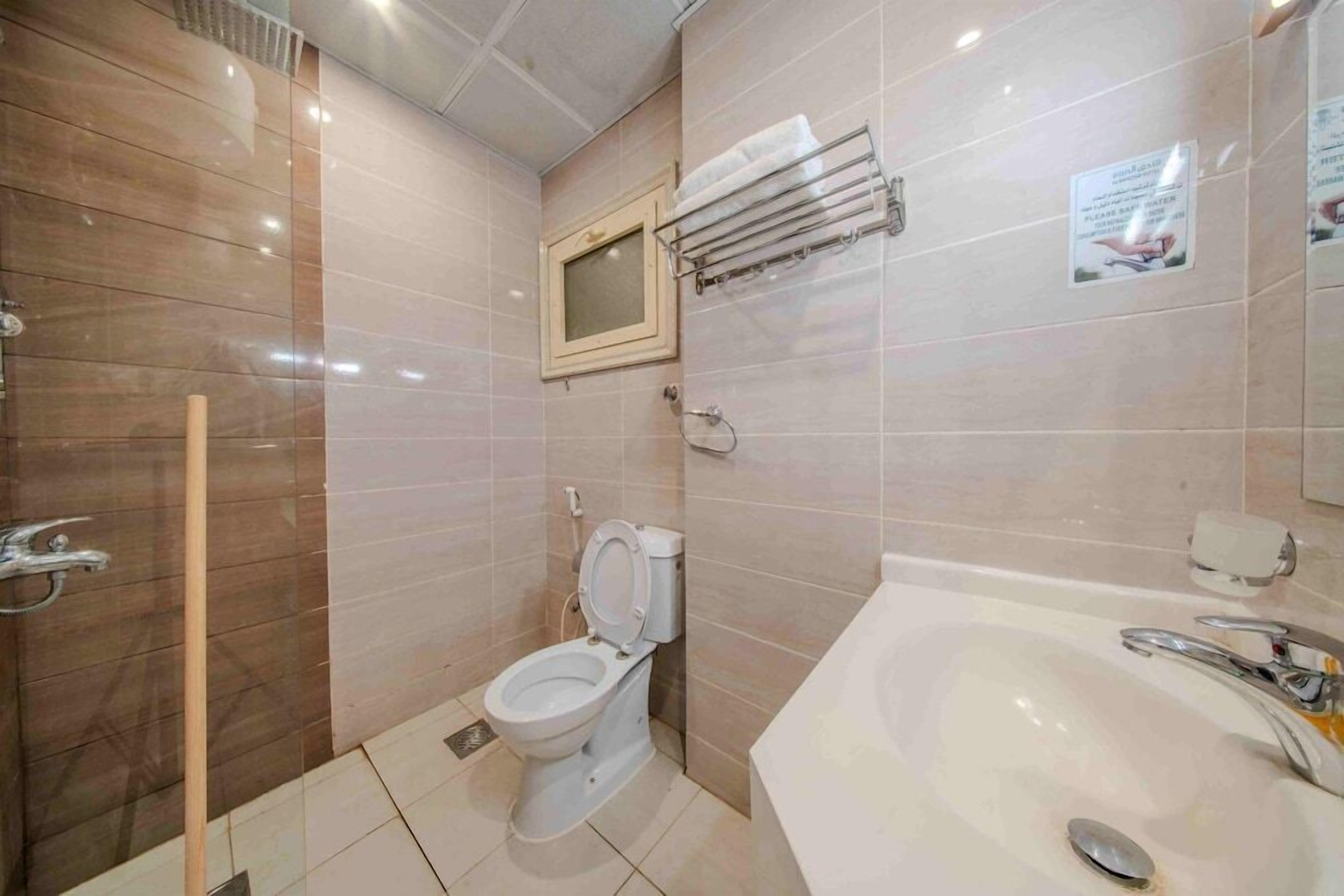 Et badeværelse med toilet, vask og bruseområde.