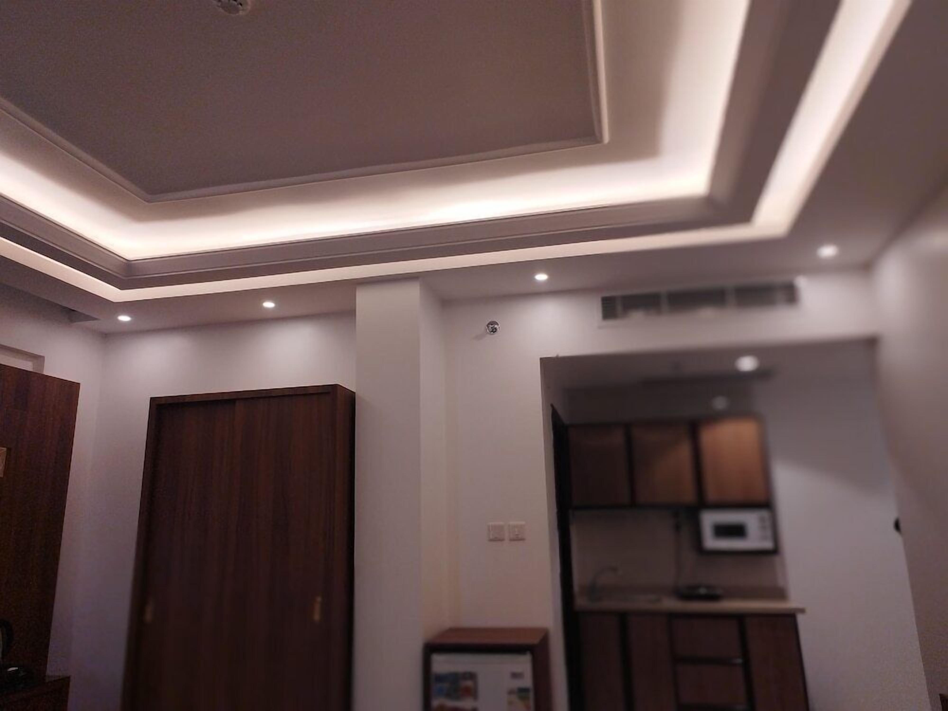 A modern interior with a recessed ceiling, wooden cabinets, and a microwave.