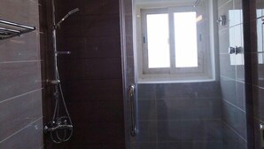Un baño moderno con ducha de vidrio, inodoro y ventana que proporciona luz natural.