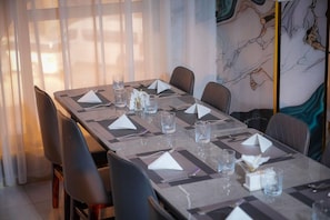 A dining table set with place settings, glasses, and a vase with flowers. - Almarzam Hotel (Madinah)