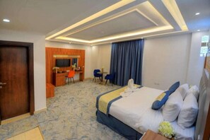Une chambre d’hôtel avec un lit, un bureau, une chaise et un téléviseur.