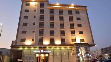 A multi-story hotel with a modern facade, illuminated windows, and a visible entrance with a sign.