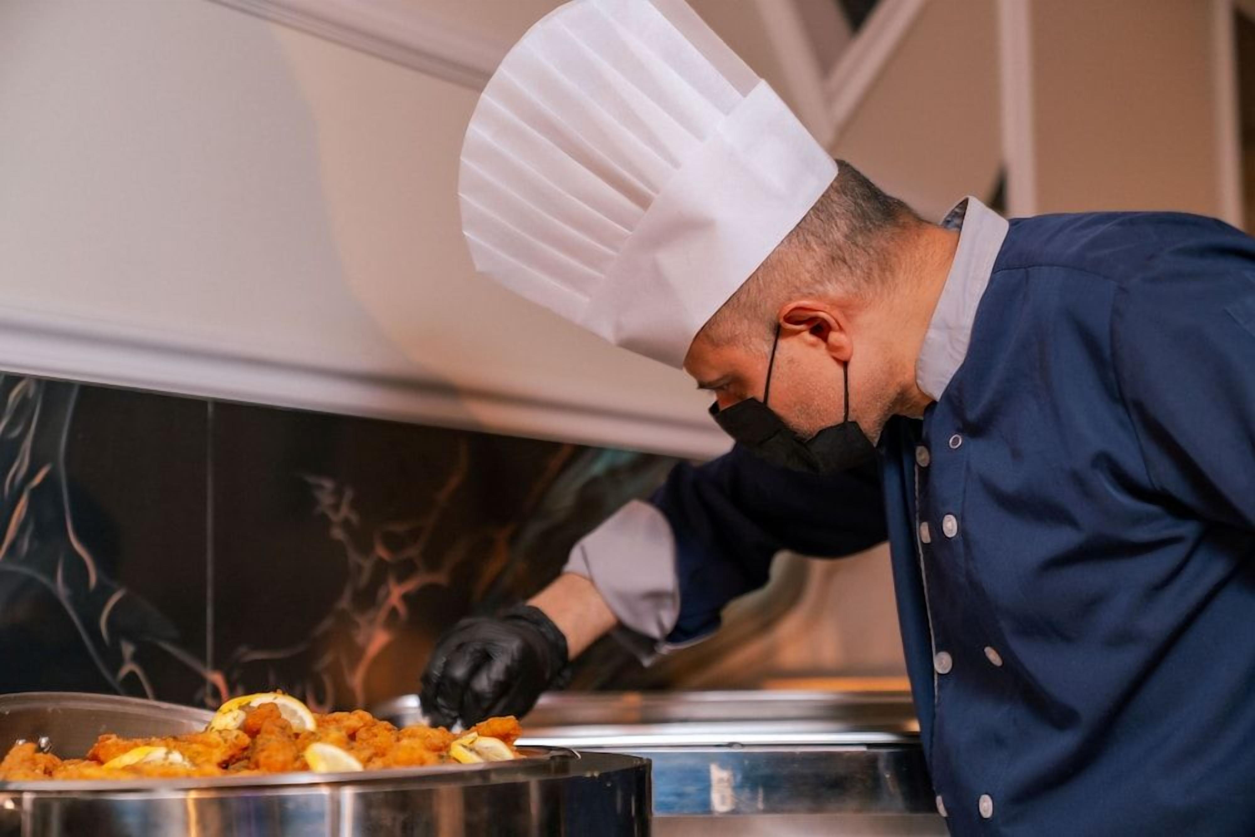 Un chef con uniforme preparando comida en una cocina.