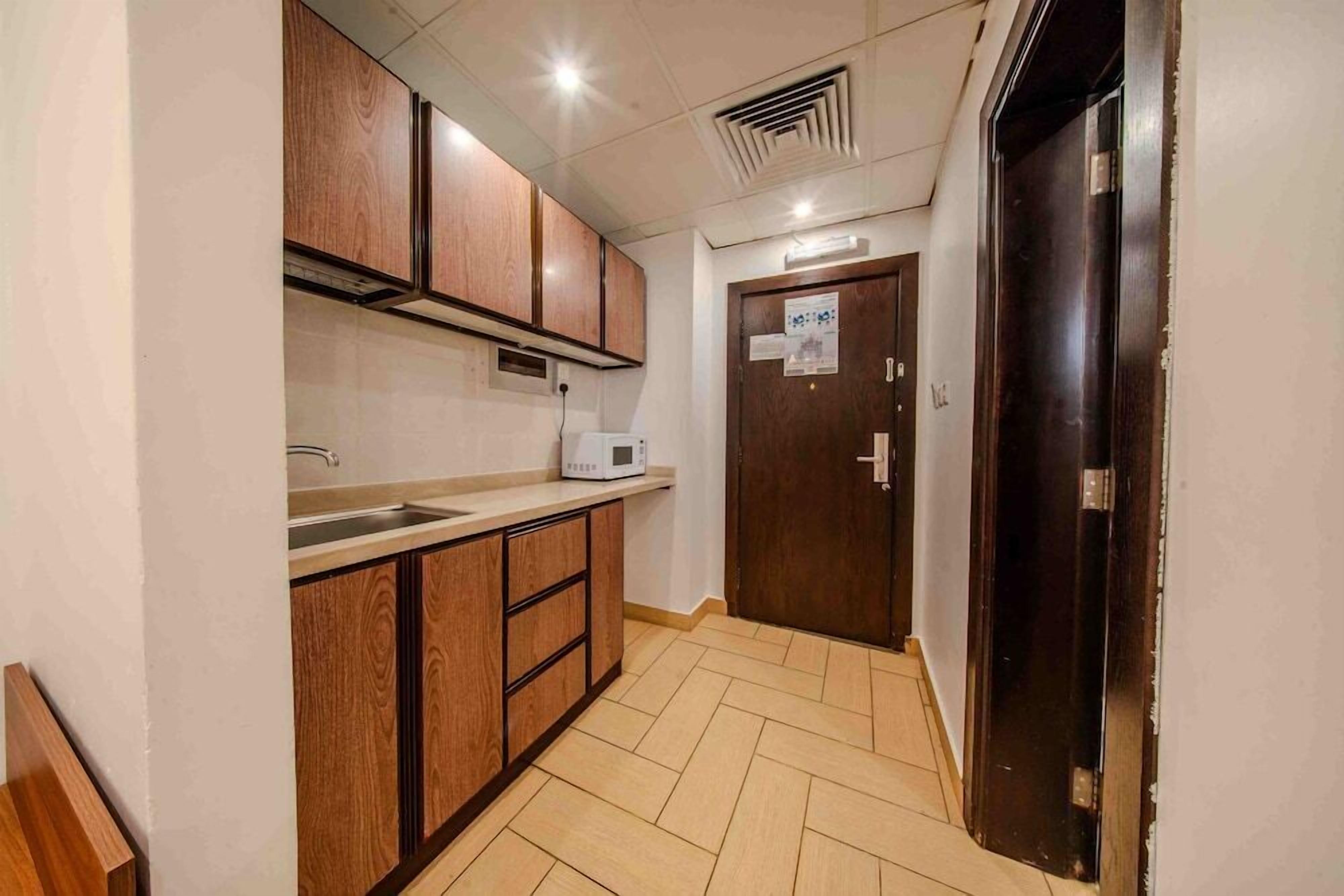 A compact kitchen with wooden cabinets, a microwave, and a sink.