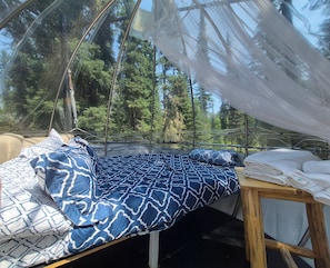 A bed with patterned bedding, a wooden table with towels, and a canopy.