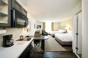 Ein Hotelzimmer mit einer Küchenzeile, einem Bett, einem Schreibtisch und einem Stuhl.