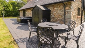 An outdoor patio with a stone building, a barbecue grill, and metal chairs. - Ardlui Church (Arrochar)