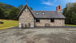 A small stone building with a sloped roof, a bell tower, and a gravel driveway. - Ardlui Church (Arrochar)