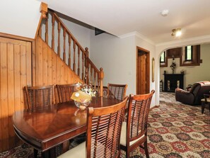 A dining area with a wooden staircase, a dining table, and chairs. - Ardlui Church (Arrochar)
