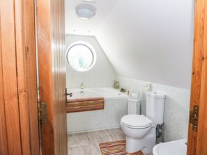 A small, compact bathroom with a toilet, sink, and bathtub. - Ardlui Church (Arrochar)