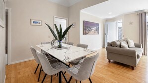 A modern living room with a grey sofa, a dining table with six chairs, and a large plant. - Park Street Retreat Cowes by Ready Set Stay (Cowes)