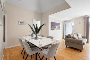 A modern living room with a grey sofa, a dining table with six chairs, and a large plant. - Park Street Retreat Cowes by Ready Set Stay (Cowes)