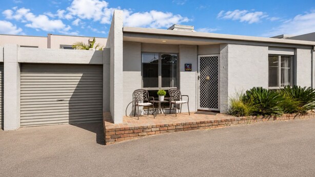 A modern building with a garage, a covered patio with chairs, and a small garden. - Park Street Retreat Cowes by Ready Set Stay (Cowes)