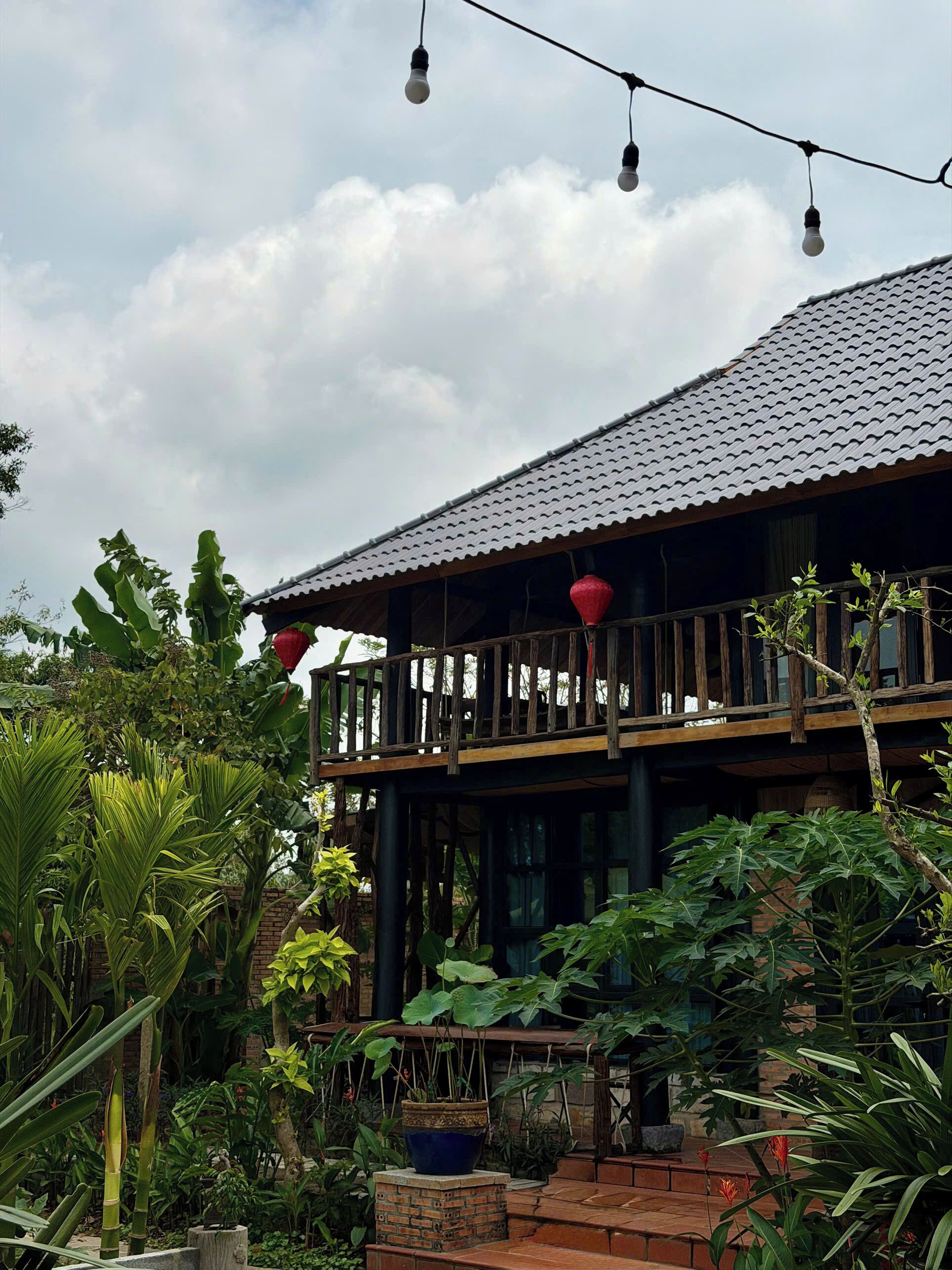 A building with a tiled roof, a wooden balcony, and surrounding greenery.