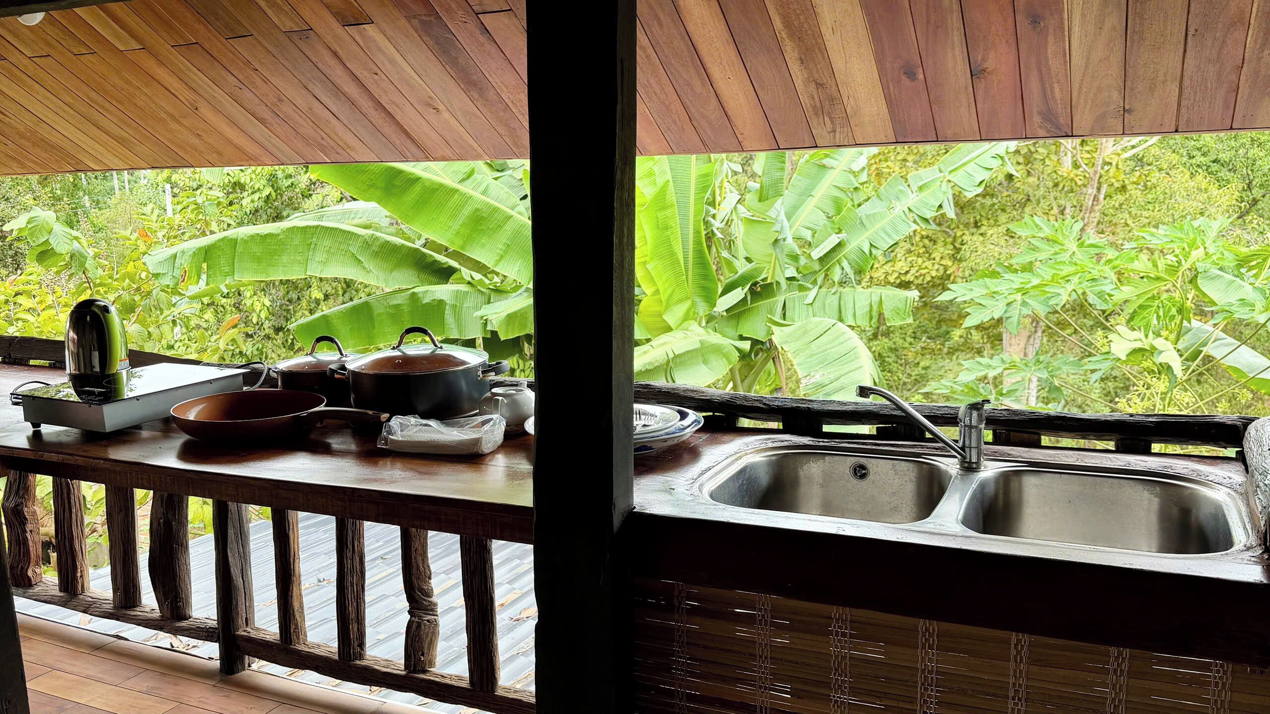 Una terraza de madera con una zona de cocina, que incluye un fregadero y diferentes utensilios.