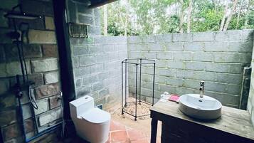Casa de banho com chuveiro, sanita e lavatório.
