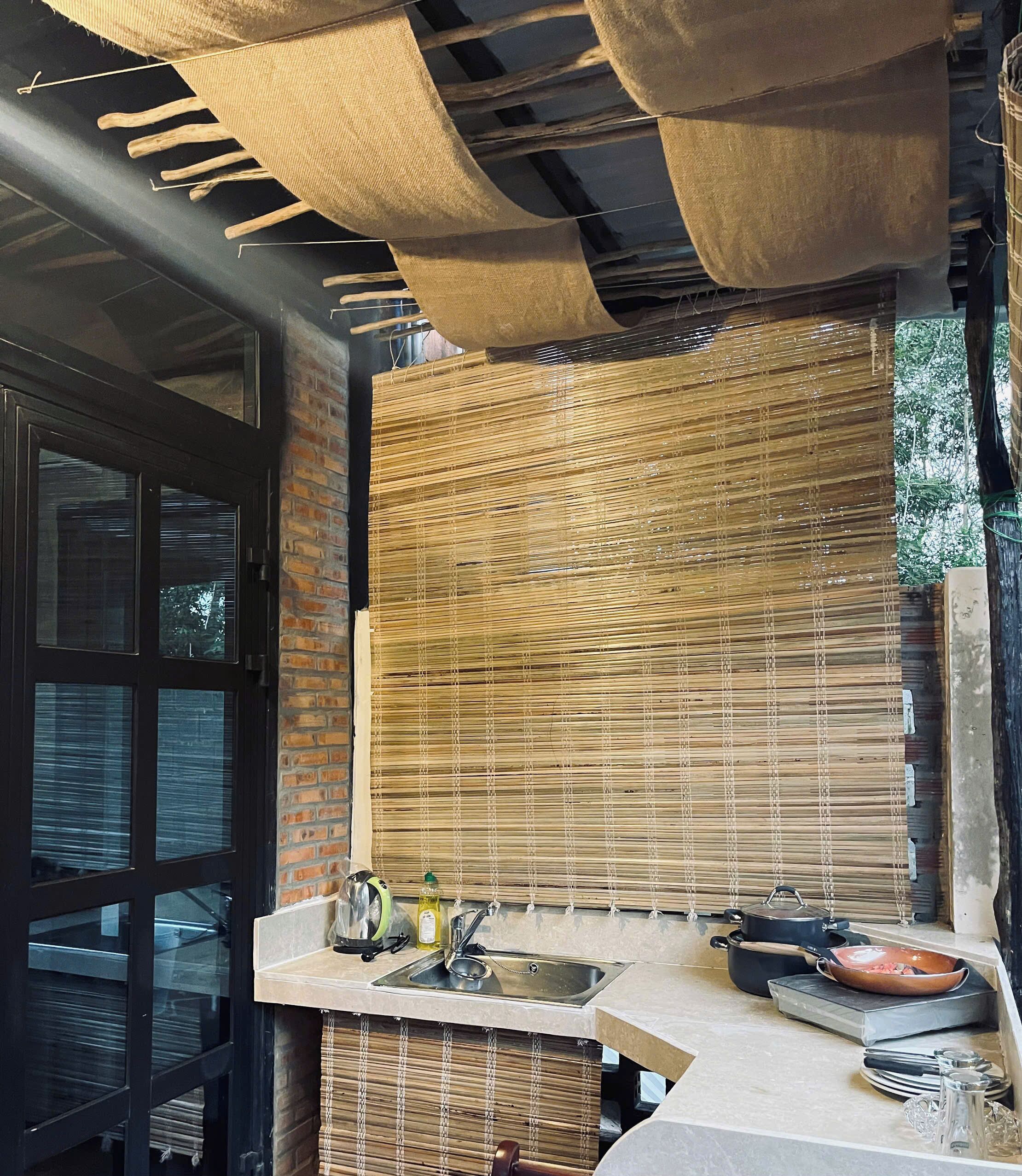 A kitchen with a built-in stove, a sink, and a window with a view of greenery.