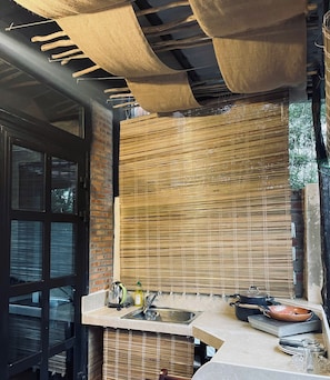 A kitchen with a built-in stove, a sink, and a window with a view of greenery.
