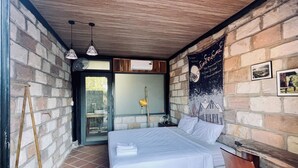 A bedroom with a bed, a wooden ladder, a window, and a wall with a poster.