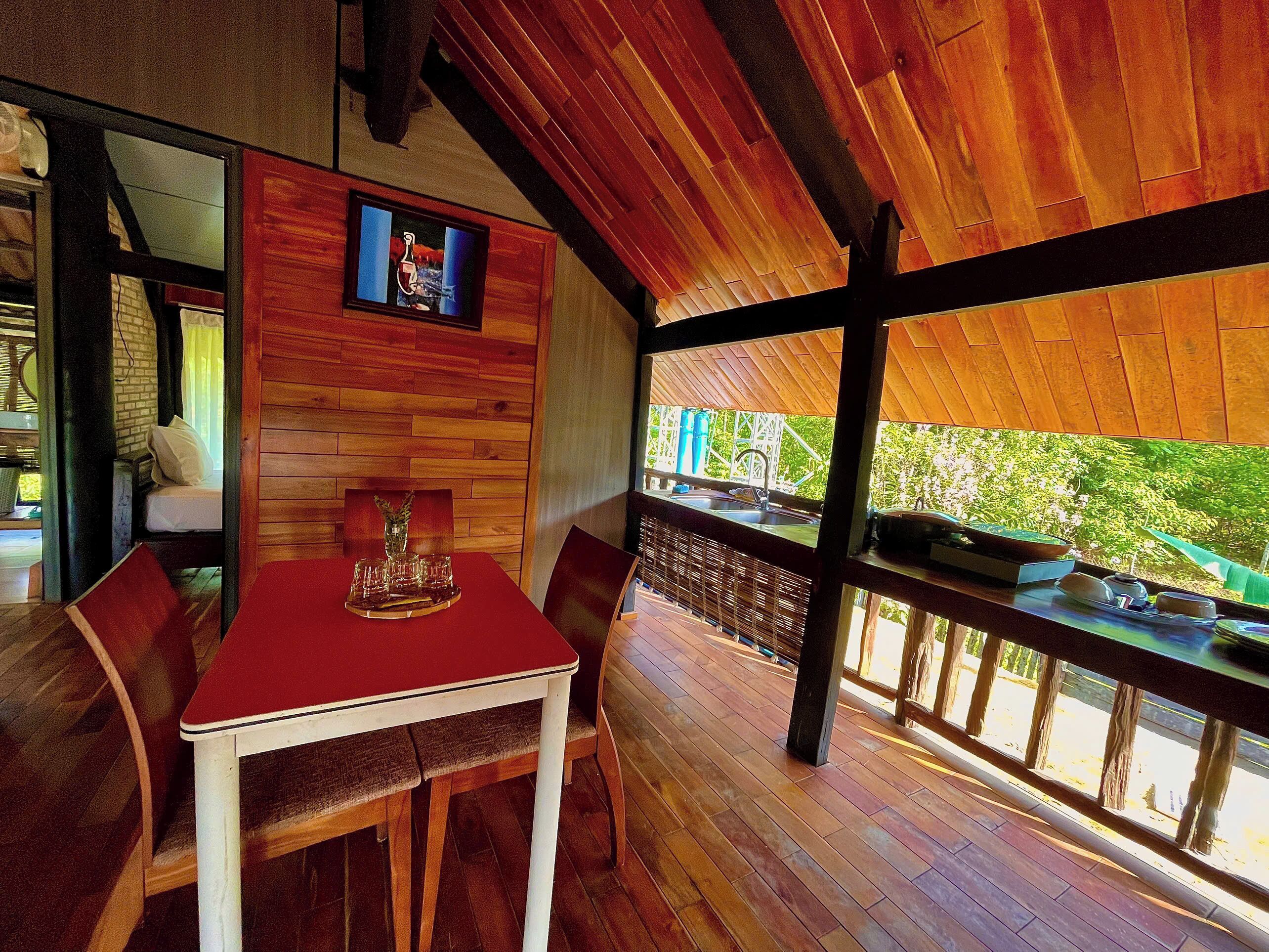 Un interior de madera con una mesa de comedor, sillas, un florero y un cuadro en la pared.