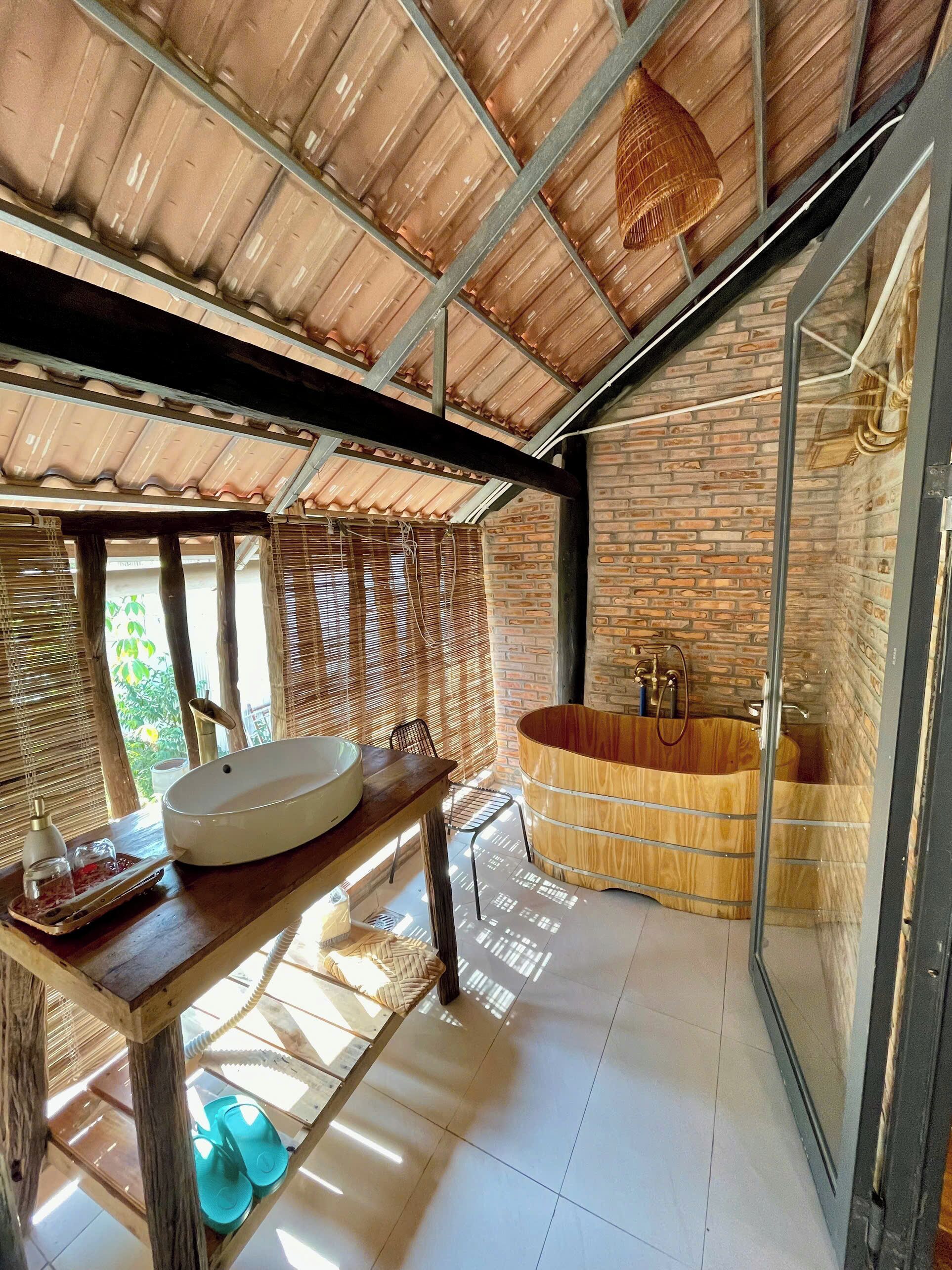 A bathroom with a large wooden bathtub, a white sink, and a glass shower enclosure.