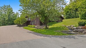 A modern house with a sloped roof, a front porch, and a well-maintained lawn. - Mountain Haven | Cozy Stowe Escape (Stowe)