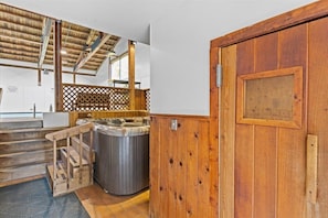 A wooden door with a metal handle, a hot tub, and a wooden staircase leading to a balcony. - Mountain Haven | Cozy Stowe Escape (Stowe)