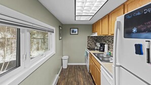 A compact kitchen with a window, a refrigerator, and a chalkboard with a pool code. - Mountain Haven | Cozy Stowe Escape (Stowe)
