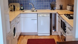 Una cucina compatta con lavatrice, lavastoviglie e piano cottura.
