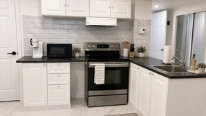 A modern kitchen with white cabinets, a black countertop, a stainless steel oven, and a microwave.