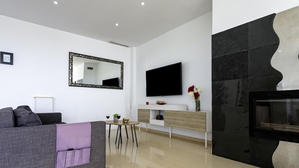 Ein modernes Wohnzimmer mit einer Couch, einem Couchtisch, einem Flachbildfernseher und einem Kamin.