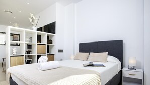 Ein modernes Schlafzimmer mit einem großen Bett, einem weißen Kleiderschrank und einem Nachttisch mit Lampe.