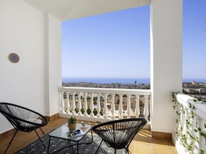 A balcony with a view of the sea, two chairs, a table, and a small plant. - Sunstay Flat Caribe. (Benalmádena)